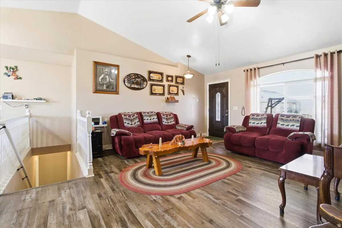 Living area with vaulted ceiling, wood finished floors, and a ceiling fan