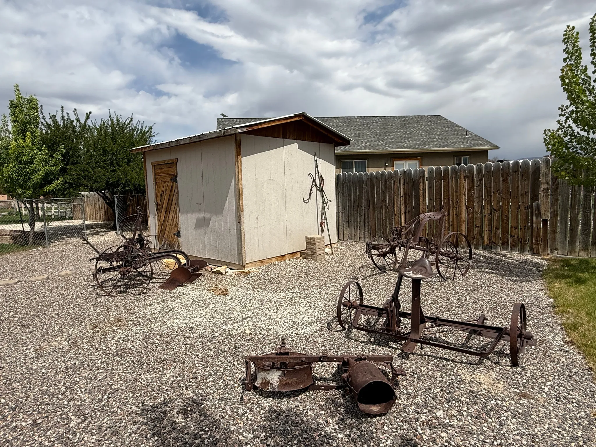 Gravel patio area featuring a storage shed with a wooden door, surrounded by a wooden privacy fence