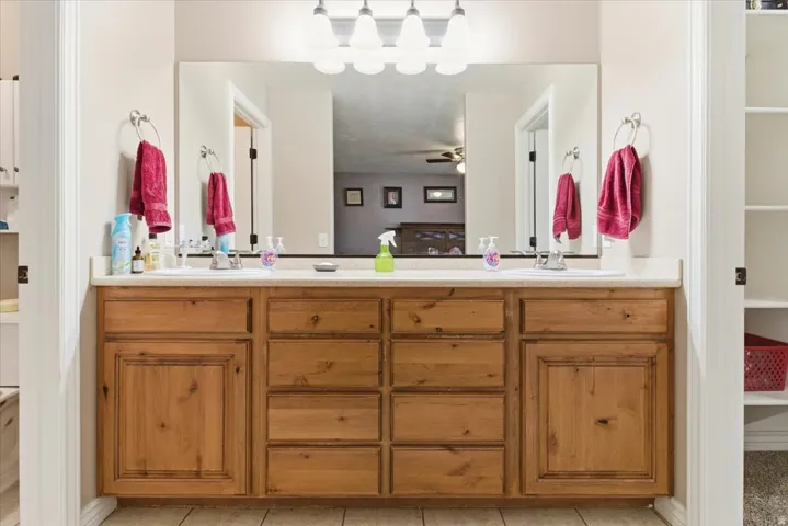 Bathroom with double vanity, light tile patterned floors, and a spacious closet