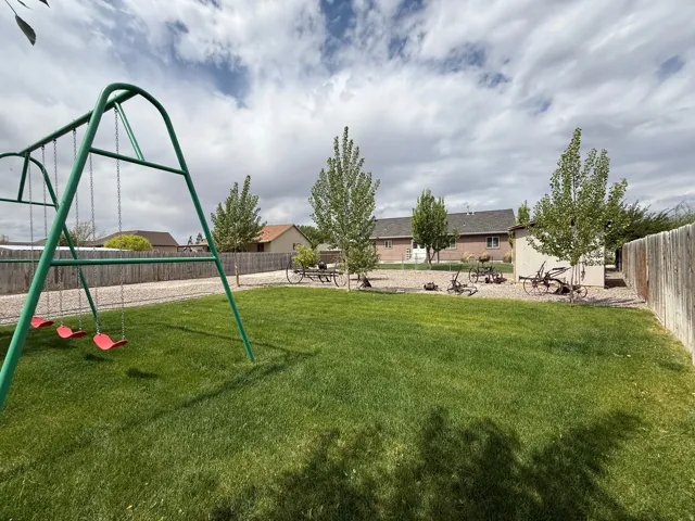Expansive backyard featuring a lush lawn, gravel perimeter, mature trees, and a storage shed