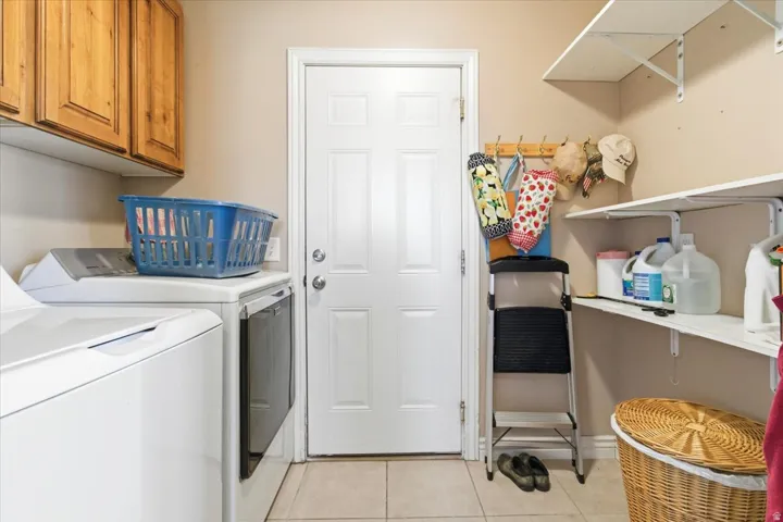 Washroom with washer and dryer, light tile patterned flooring, and cabinet space