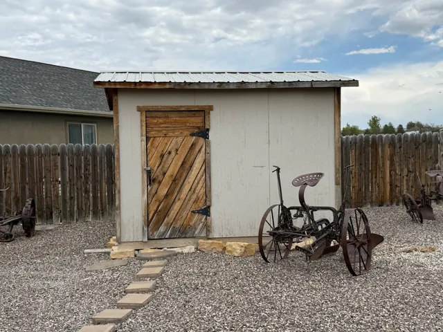 Storage shed with a corrugated metal roof, wooden door, and light-colored siding