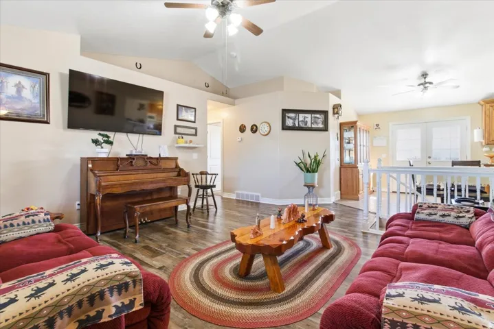 Living room featuring ceiling fan, lofted ceiling, and wood finished floors