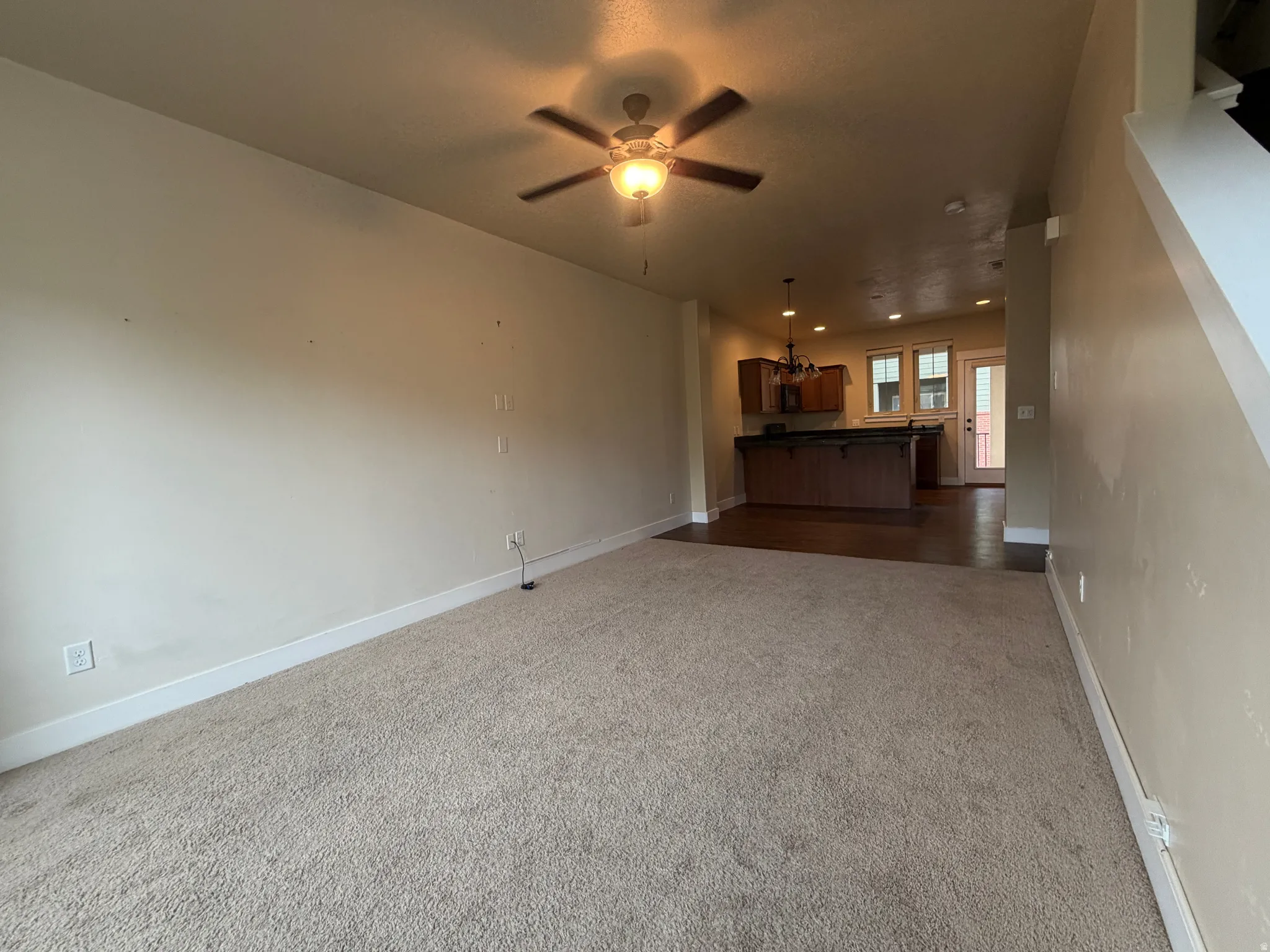 Unfurnished living room with a ceiling fan and dark carpet