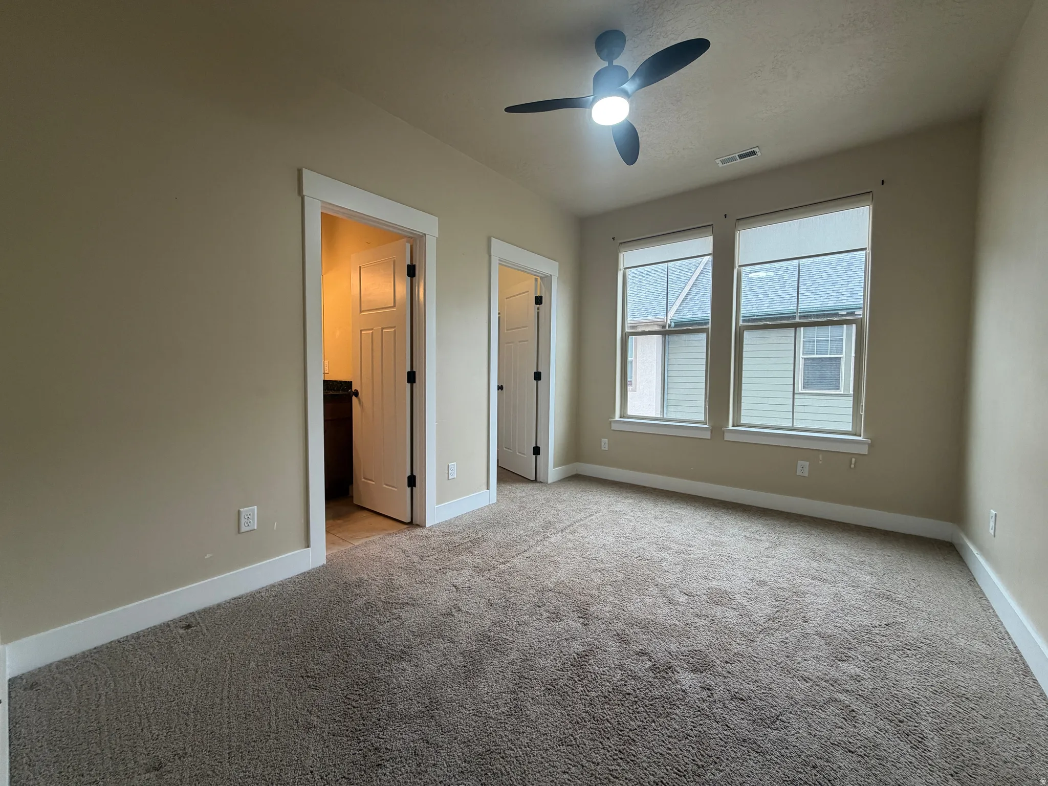 Unfurnished bedroom featuring a spacious closet, light colored carpet, ceiling fan, and a textured ceiling