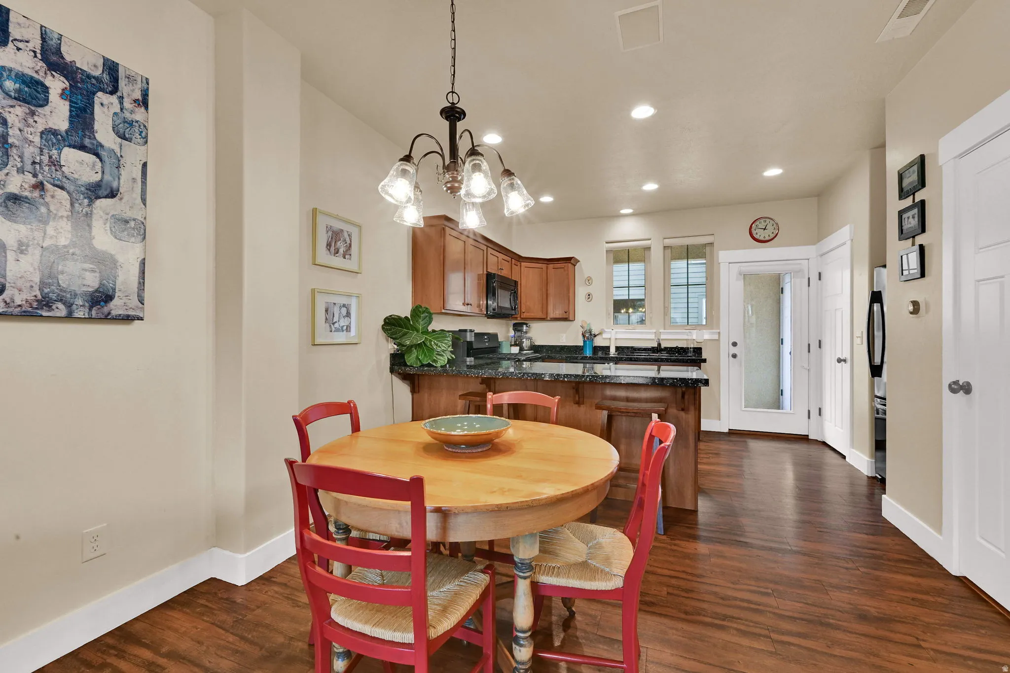 Dining space with dark wood-type flooring, recessed lighting, and a chandelier