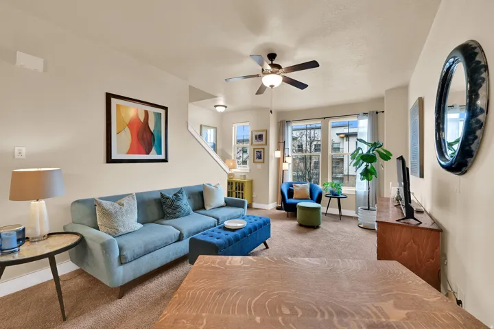 Carpeted living area with a ceiling fan and baseboards