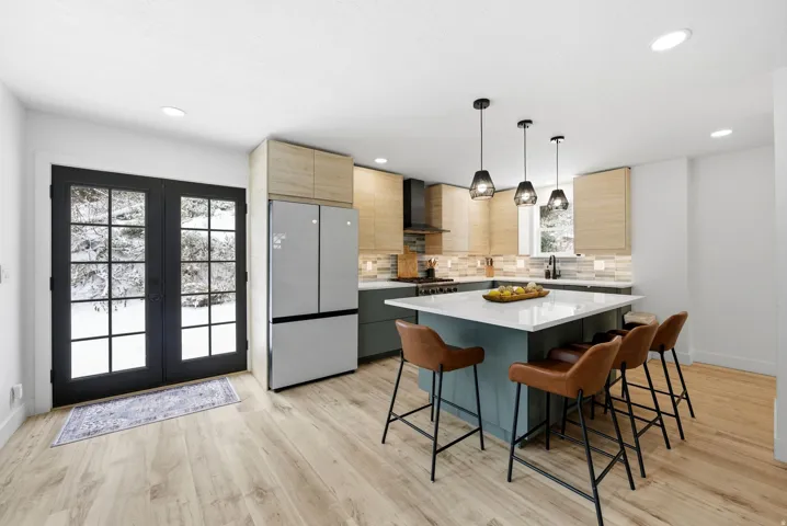 Kitchen with a center island, hanging light fixtures, a kitchen bar, freestanding refrigerator, and light brown cabinets
