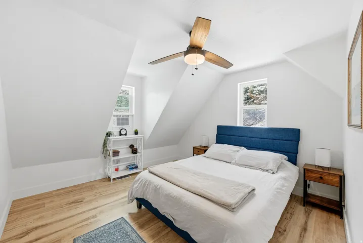 Bedroom with light wood finished floors, lofted ceiling, and ceiling fan