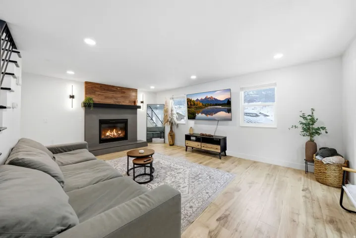 Living area with light wood-style floors, a large fireplace, and recessed lighting