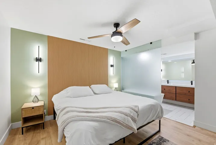 Bedroom with light wood finished floors, a ceiling fan, and ensuite bath