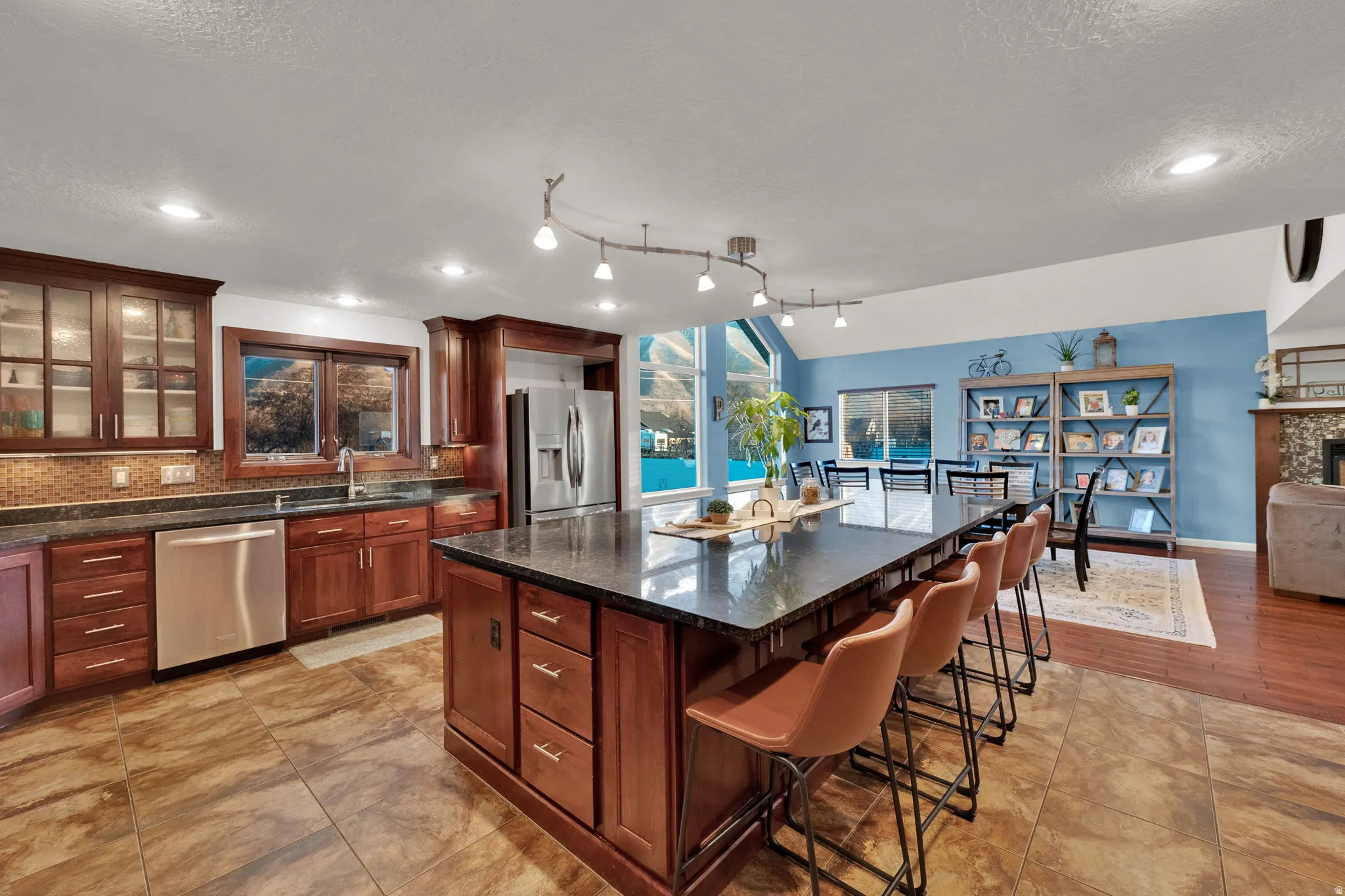 Kitchen featuring dark stone countertops, glass insert cabinets, appliances with stainless steel finishes, lofted ceiling, and recessed lighting