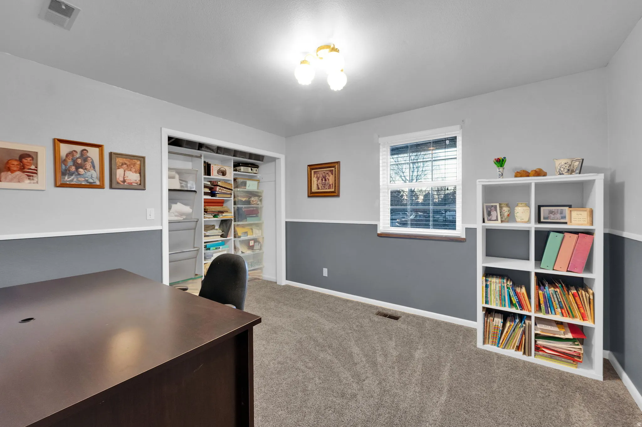 Home office with light colored carpet and built in shelves