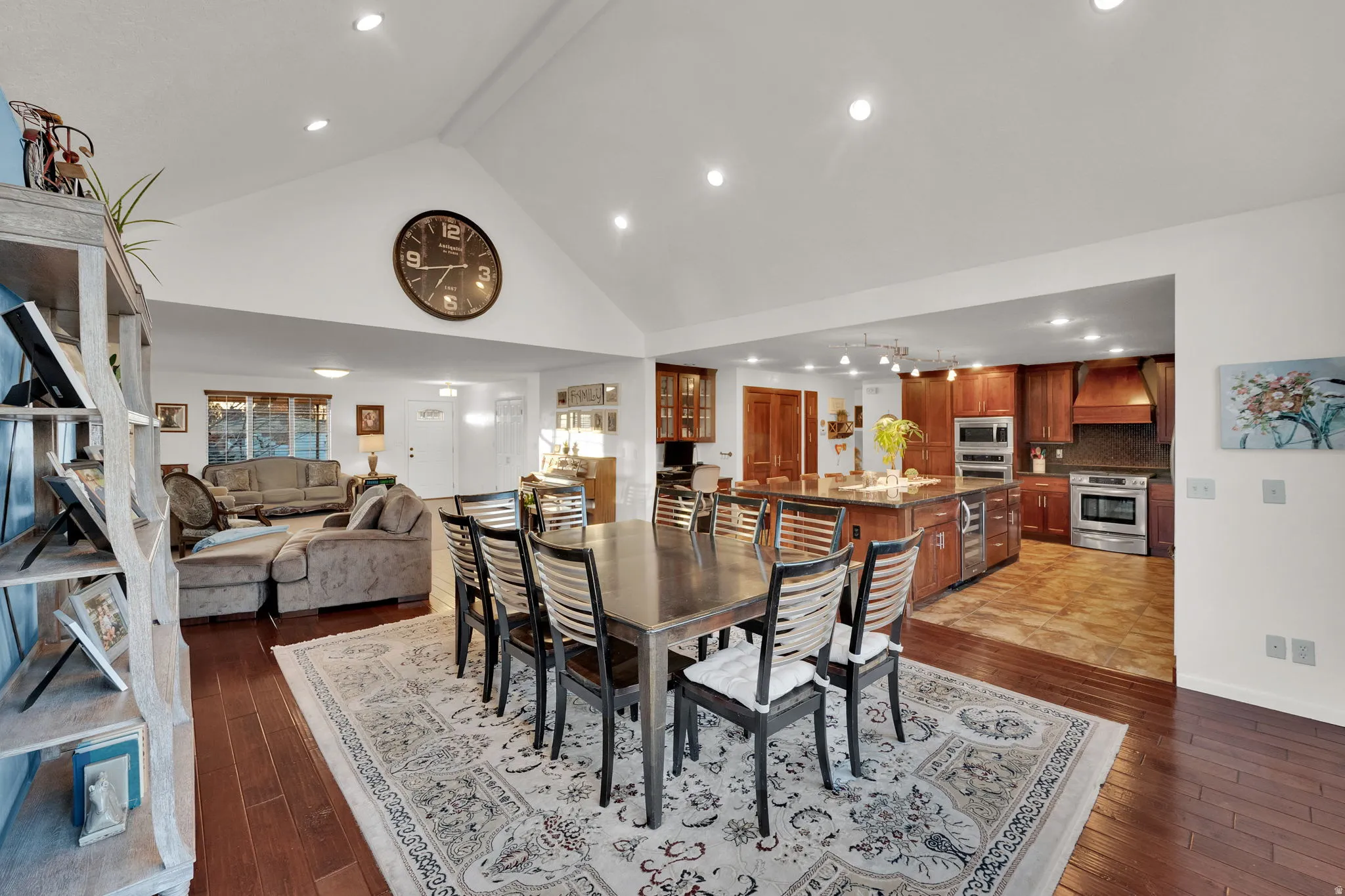 Dining room with dark wood finished floors, high vaulted ceiling, and recessed lighting