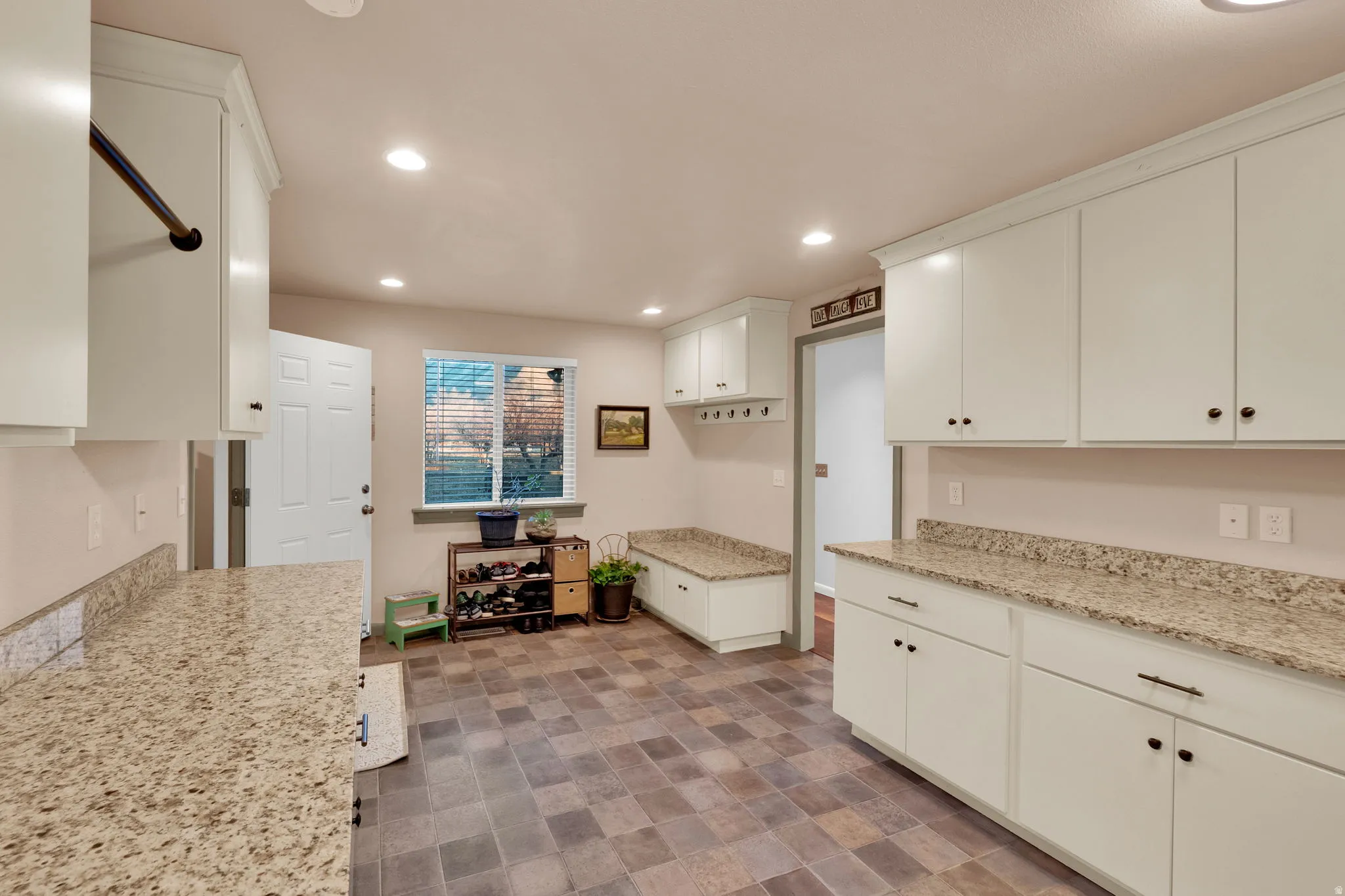 Kitchen featuring light stone counters, recessed lighting, white cabinetry, and stone finish flooring