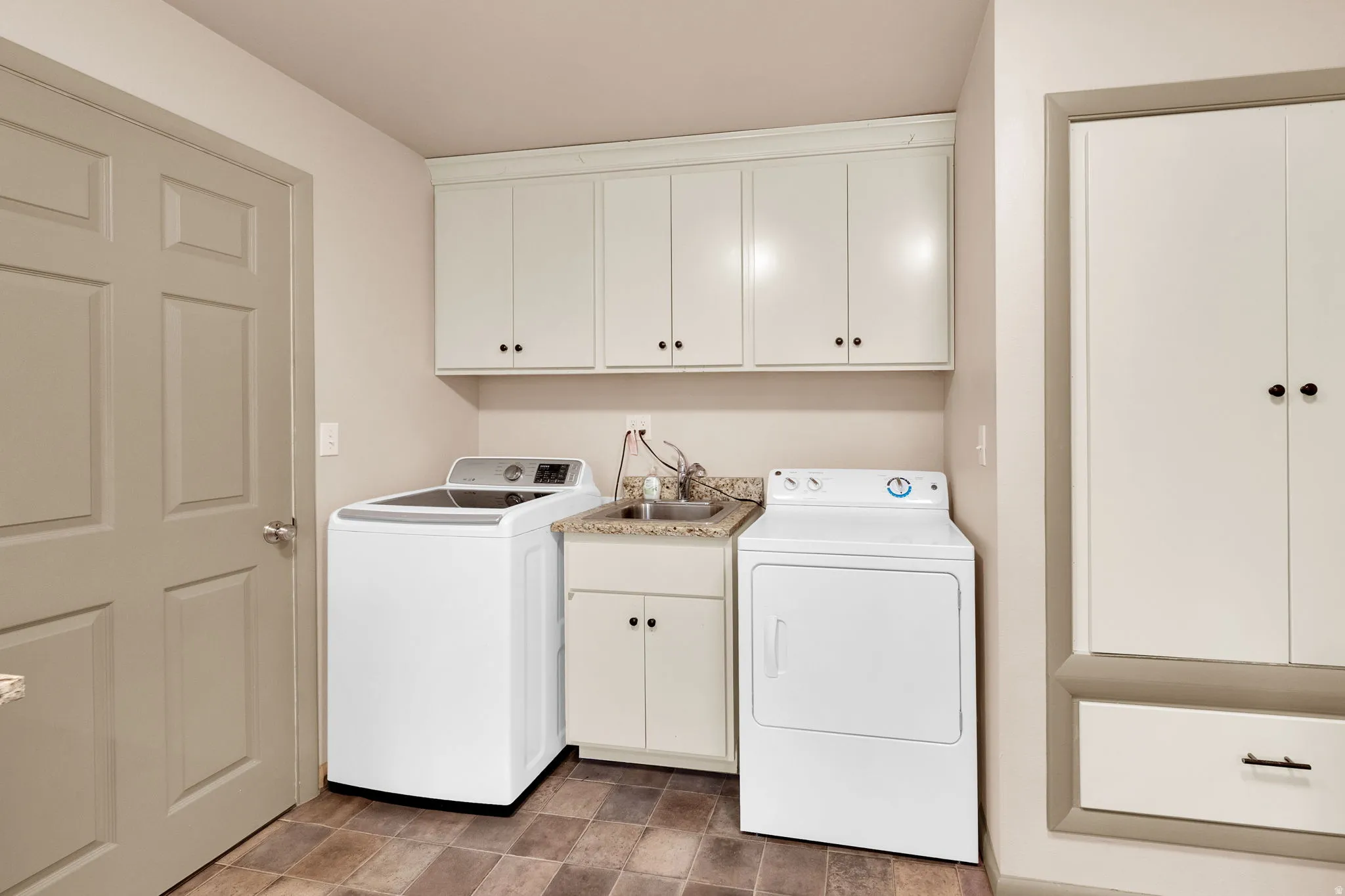 Washroom with cabinet space and washing machine and clothes dryer