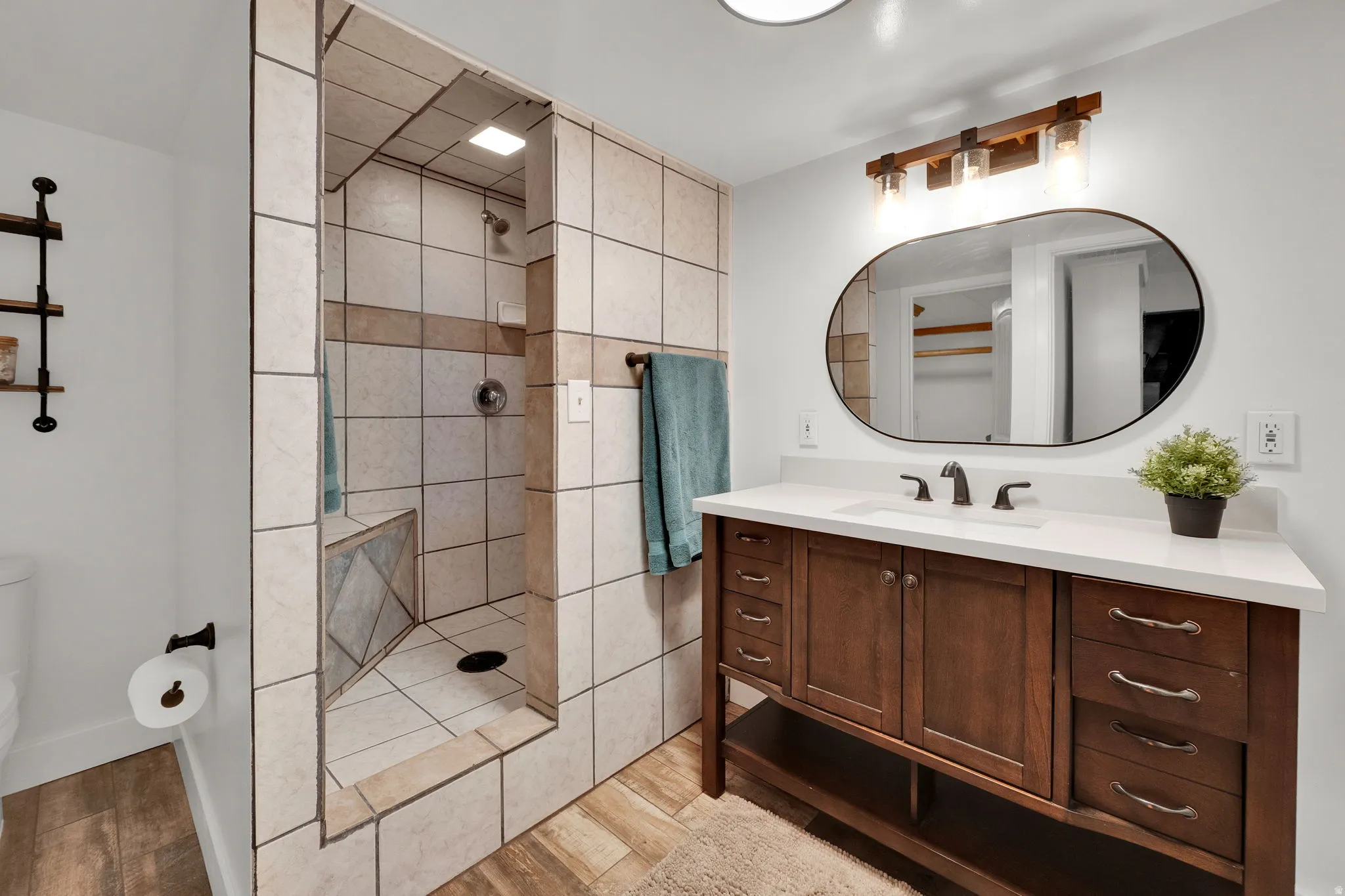 Full bathroom with vanity, a walk in shower, and light wood finished floors