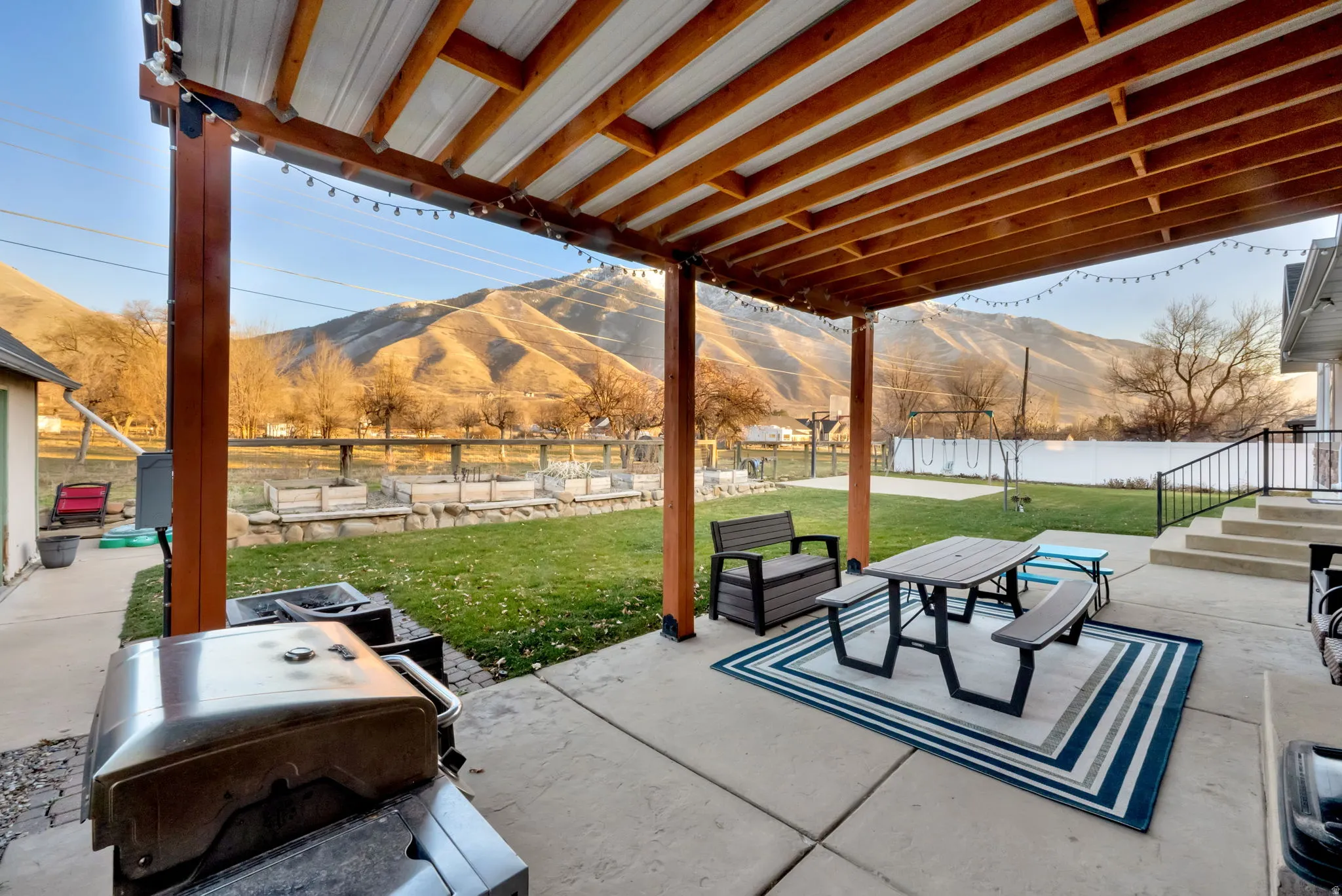 Fenced backyard featuring a patio, a mountain view, outdoor dining area, and a grill