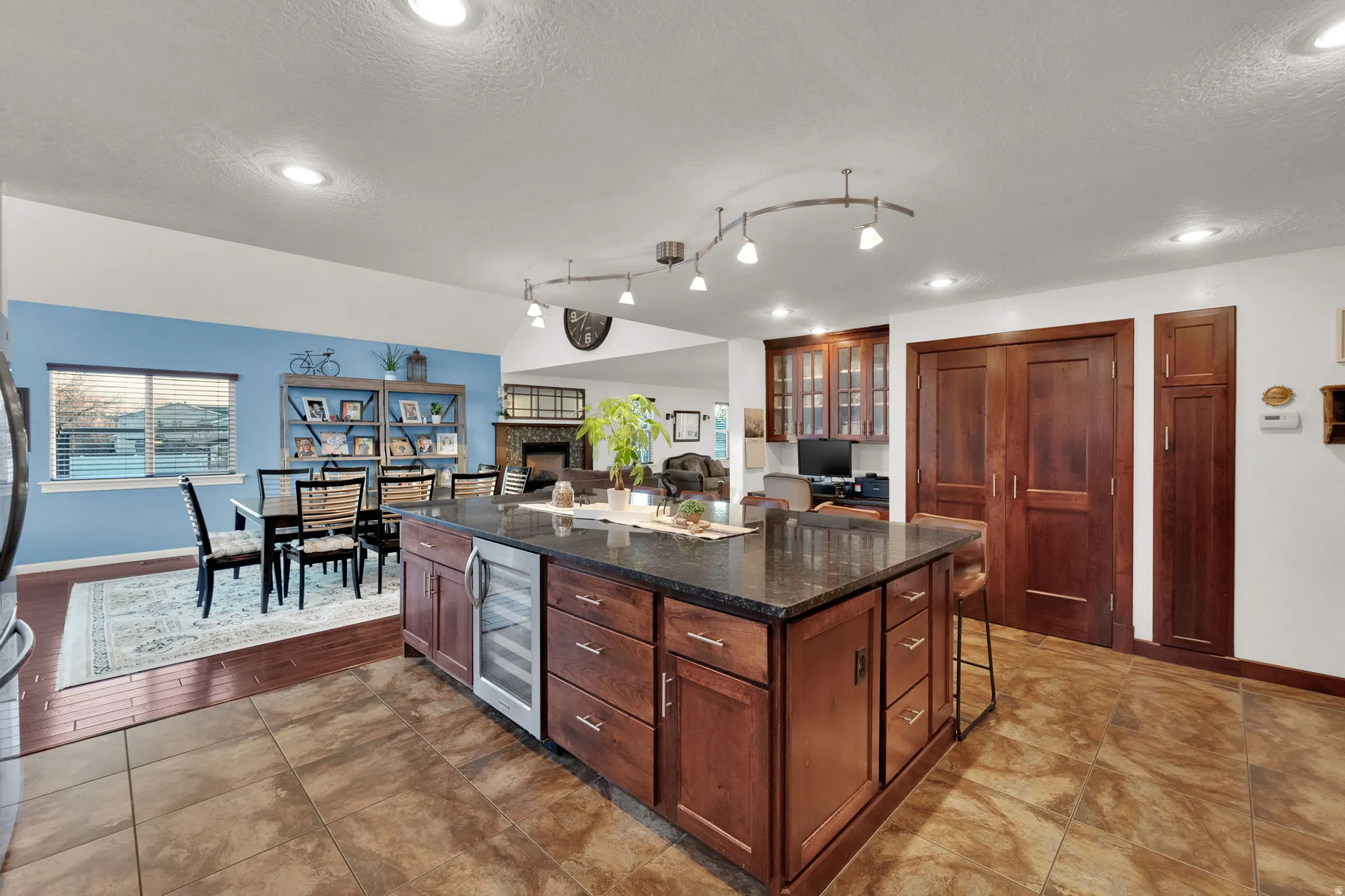 Kitchen with a breakfast bar area, a center island, dark stone countertops, a fireplace, and beverage cooler