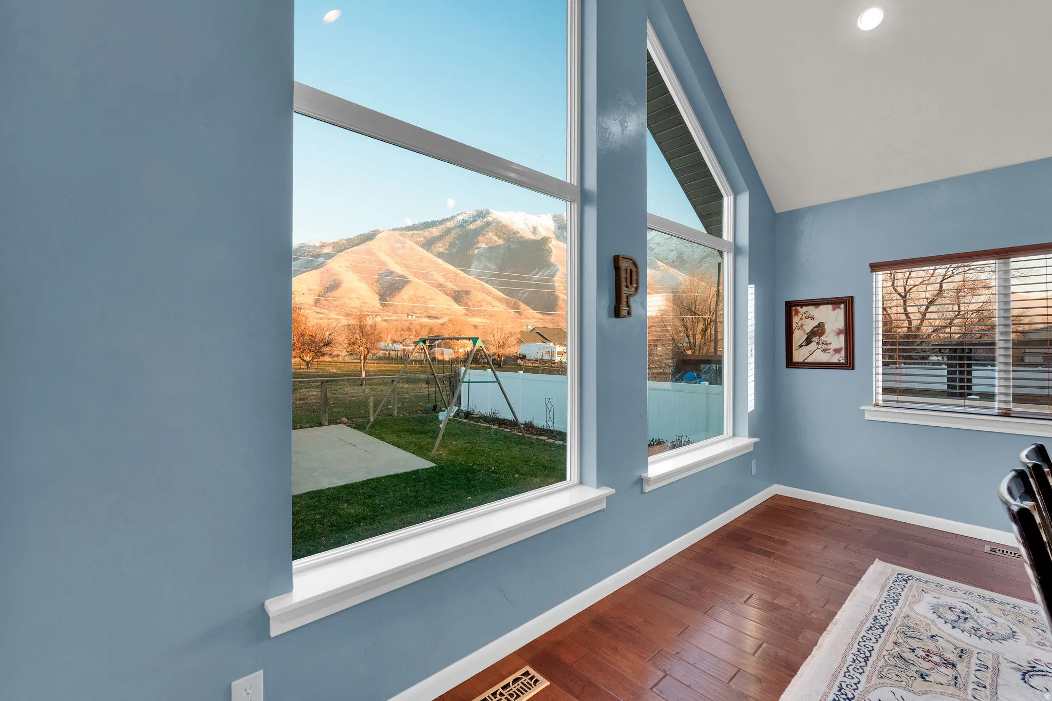 Unfurnished room featuring healthy amount of natural light, a mountain view, dark wood-style floors, recessed lighting, and vaulted ceiling