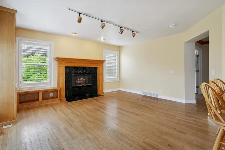 Living room with track lighting, light wood-style flooring, healthy amount of natural light, and a high end fireplace