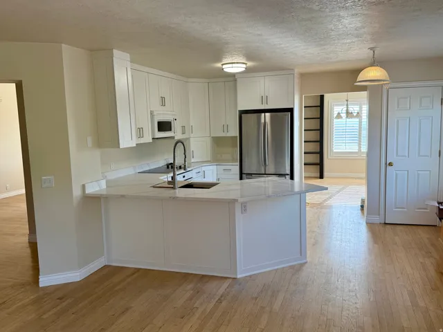 Spacious kitchen featuring white shaker cabinetry, stainless steel appliances, and light-toned wood-finish flooring