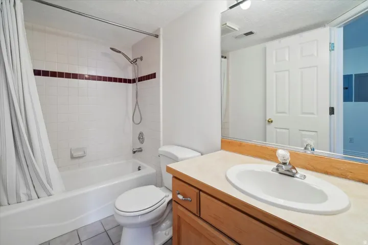 Bathroom with shower / tub combo with curtain, vanity, a textured ceiling, light tile patterned flooring, and electric panel