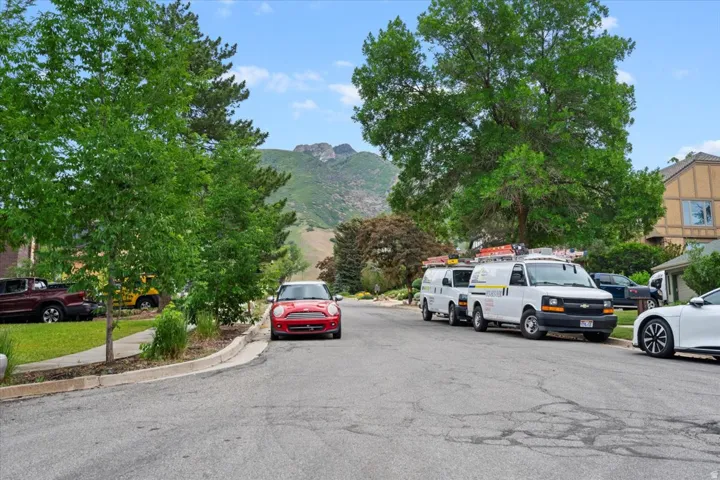View of asphalt street featuring a mountain view, curbs, and sidewalks