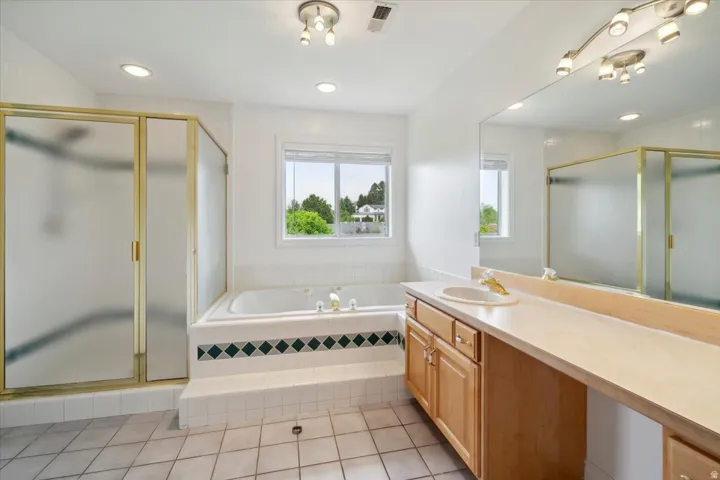 Bathroom with a garden tub, vanity, a shower stall, light tile patterned floors, and recessed lighting