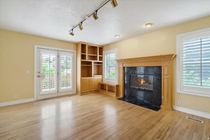 Living room with track lighting, a premium fireplace, light wood-style flooring, radiator heating unit, and a textured ceiling