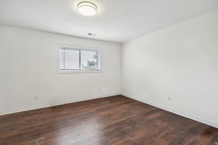 Basement living featuring a textured ceiling and dark wood finished floors