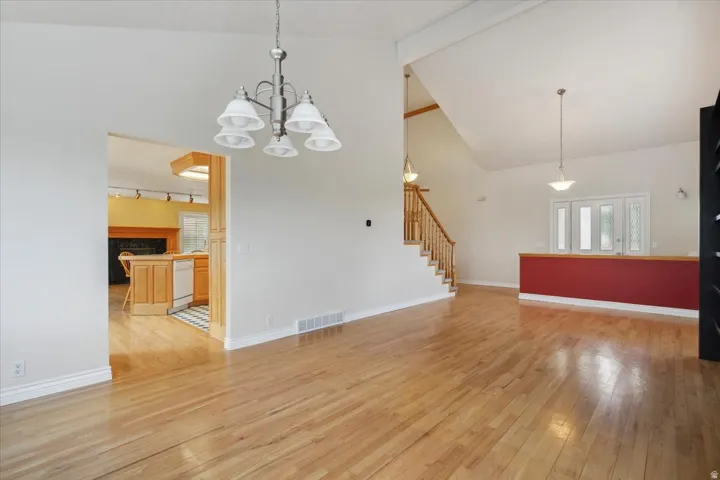 Living room with light wood finished floors, beam ceiling, high vaulted ceiling, stairway, and a premium fireplace
