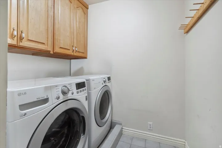 Laundry room featuring washing machine and dryer, light tile patterned flooring, and cabinet space