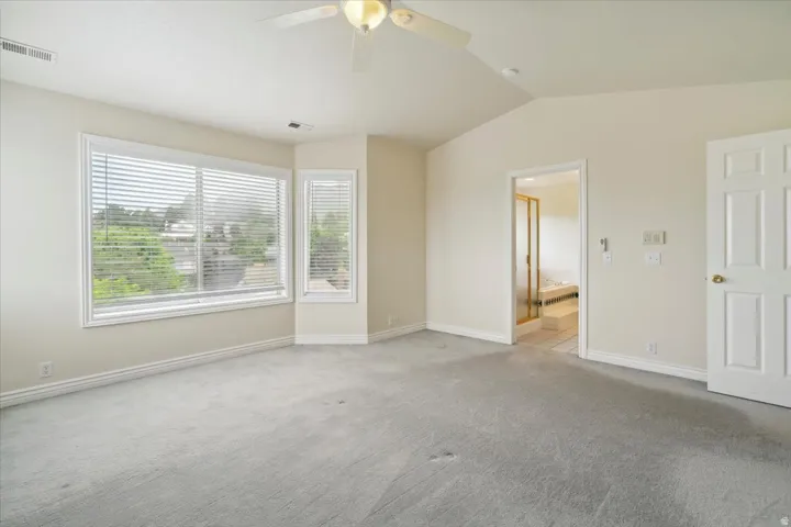 Bedroom with vaulted ceiling, carpet, and a ceiling fan