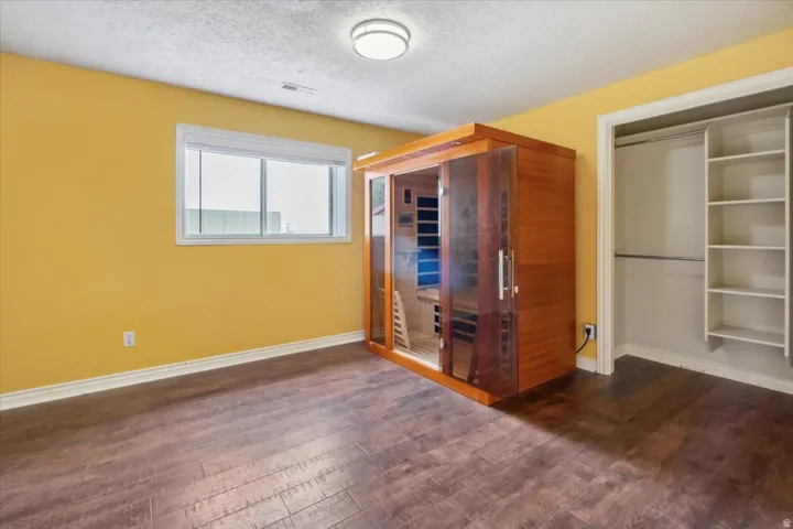 Basement bedroom with a relaxing sauna, a textured ceiling, and dark wood-style flooring