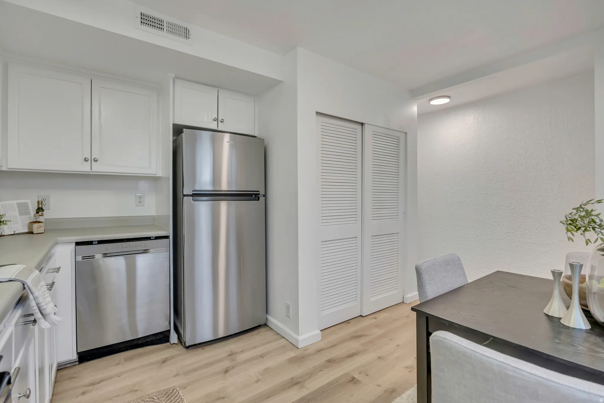 Kitchen featuring white cabinetry, appliances with stainless steel finishes, light countertops, and light wood finished floors