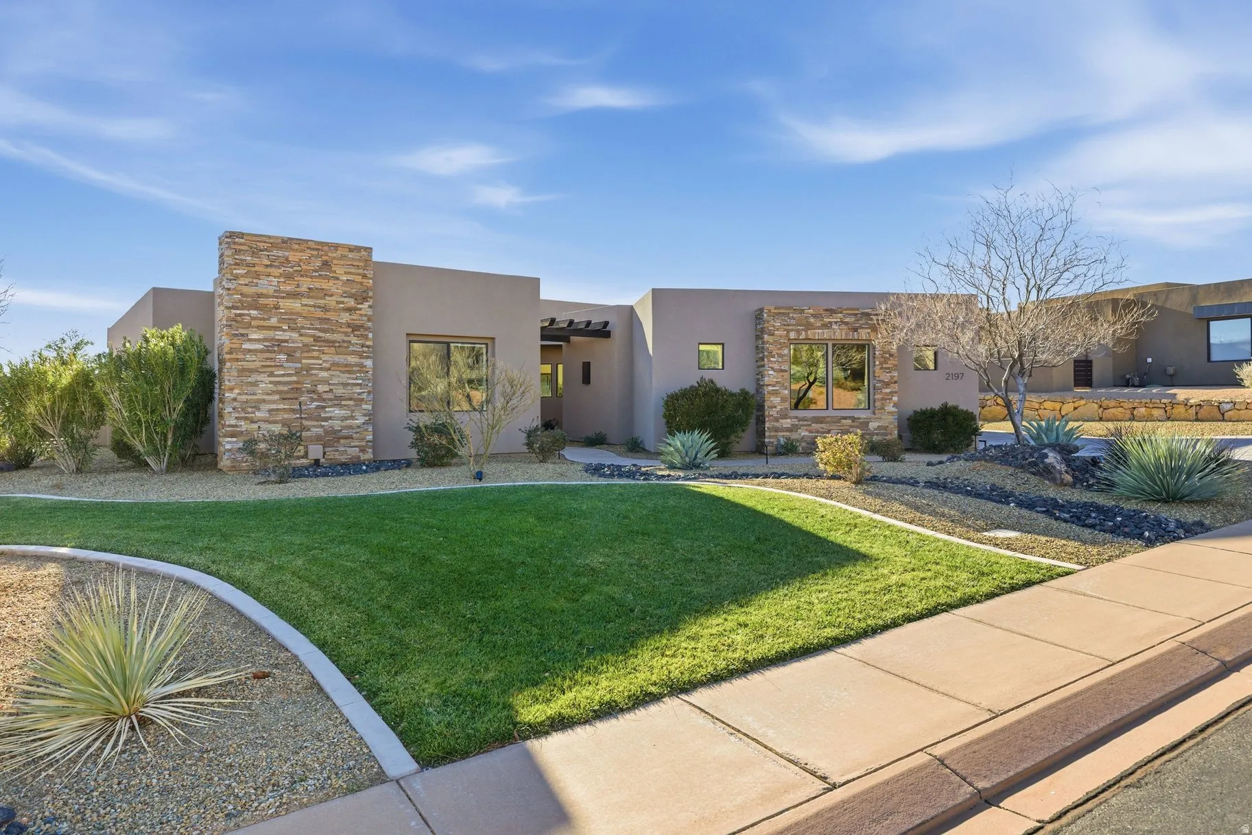 View of front of property with stone siding, stucco siding, and a front yard