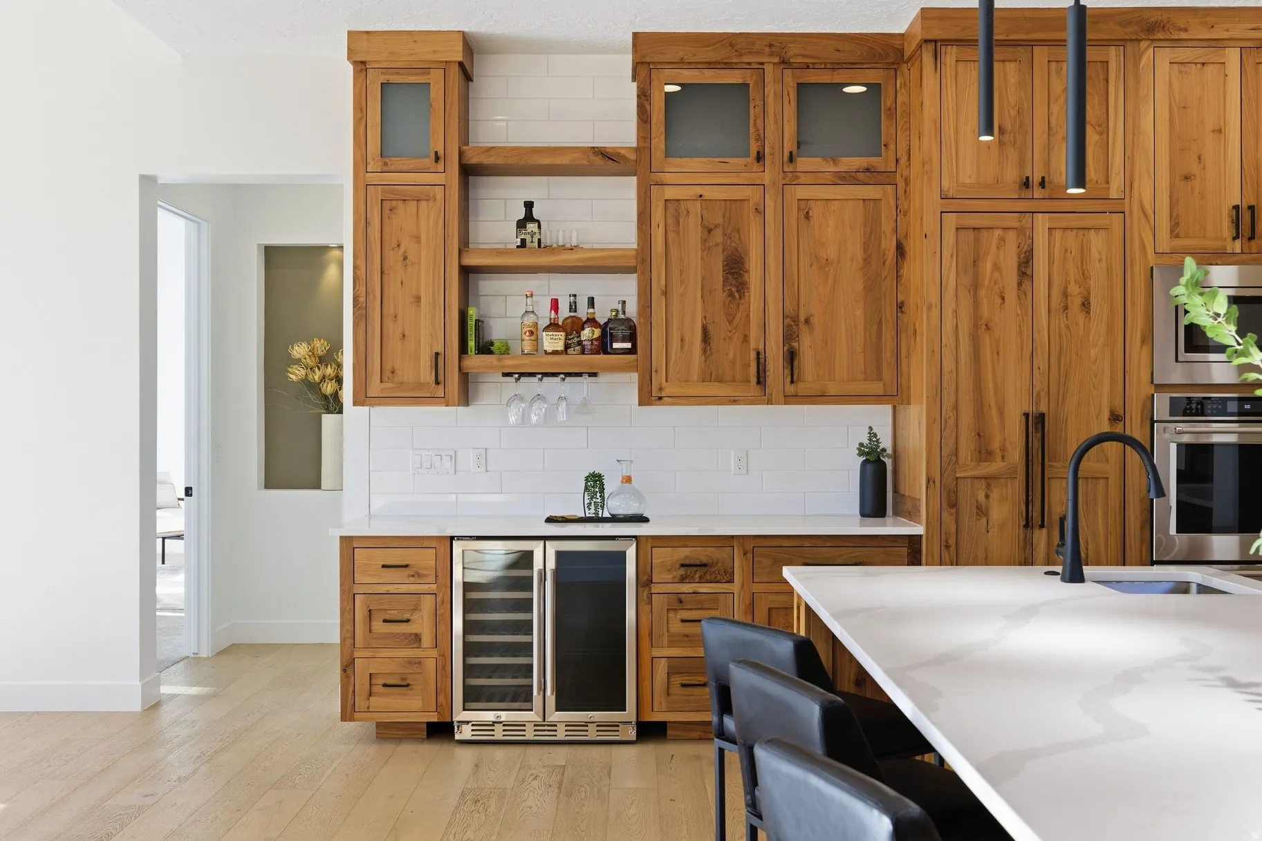 Indoor dry bar with beverage cooler, wood finish cabinets, stainless steel appliances, tasteful backsplash, and light wood-style floors