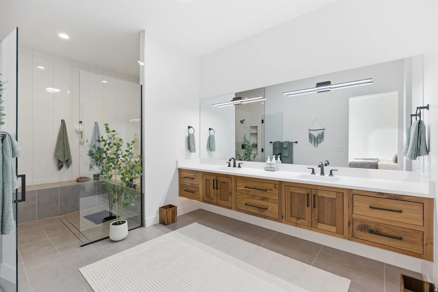 Bathroom with double vanity, a stall shower, light tile patterned floors, and recessed lighting
