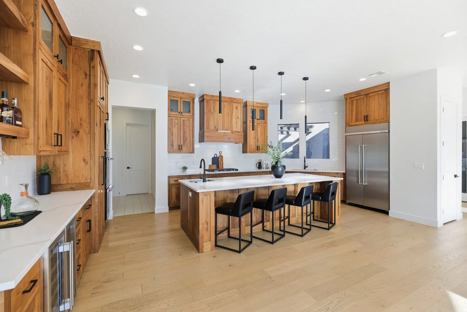 Kitchen with wood finish cabinetry, glass fronted cabinets, an island with sink, built in fridge, and light wood-style flooring