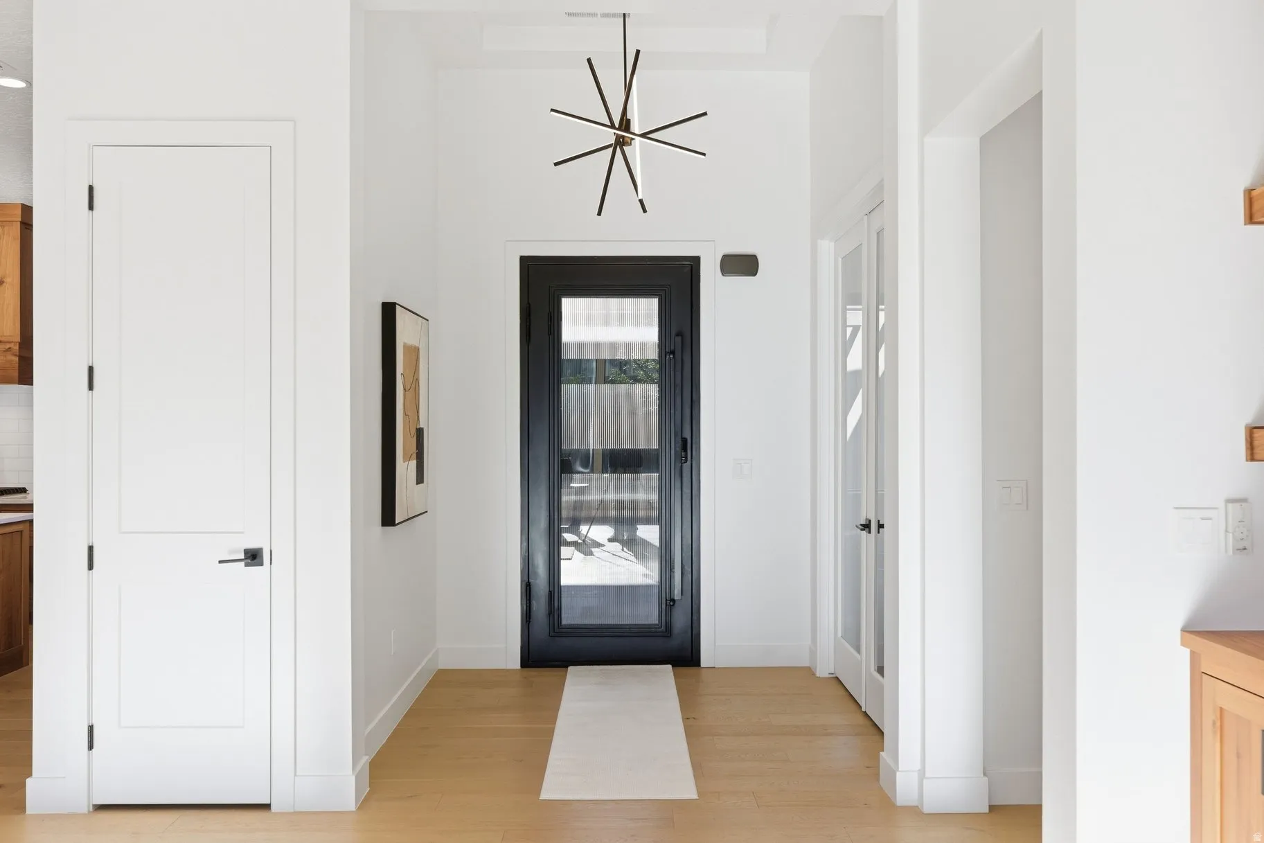 Entryway featuring light wood finished floors and suspended lighting