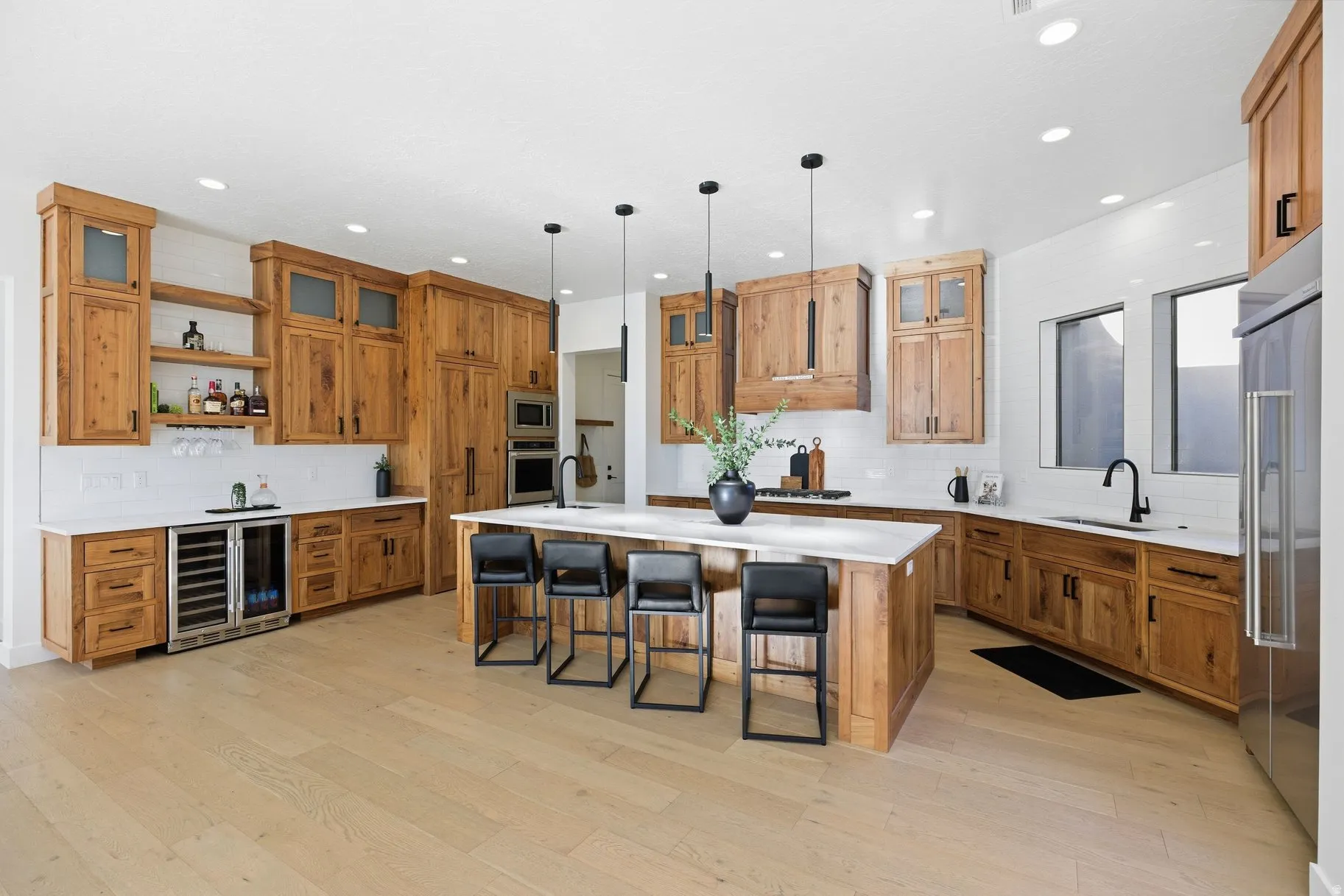 Kitchen with a spacious island, wood finish cabinets, a kitchen bar, open shelves, and beverage cooler