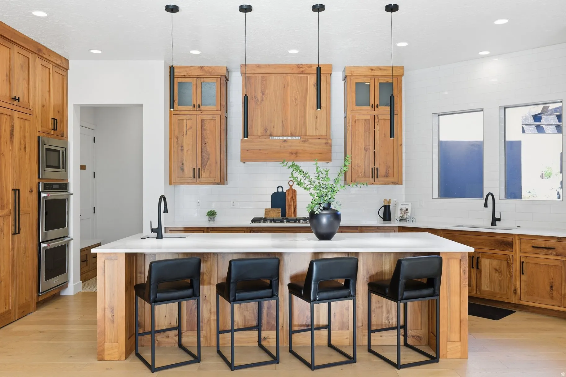 Kitchen featuring an island with sink, wood finish cabinets, a kitchen bar, pendant lighting, and light wood finished floors