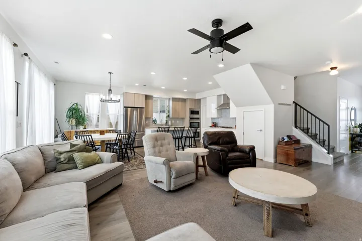 Living area featuring stairway, light wood-style flooring, a ceiling fan, recessed lighting, and a chandelier