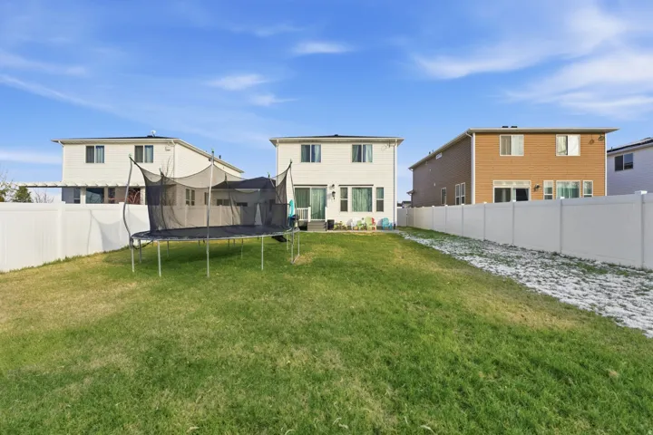 Rear view of house featuring a trampoline and a fenced backyard