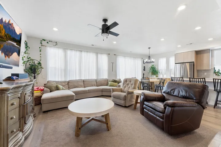 Living area featuring light wood finished floors, healthy amount of natural light, and a ceiling fan