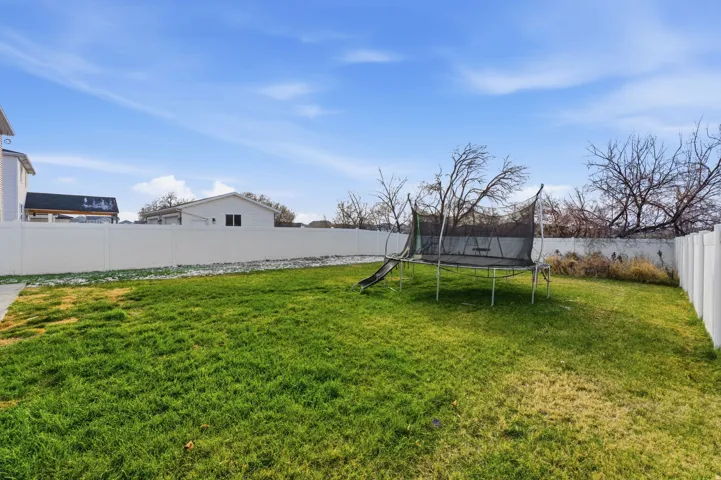 Fenced backyard featuring a trampoline