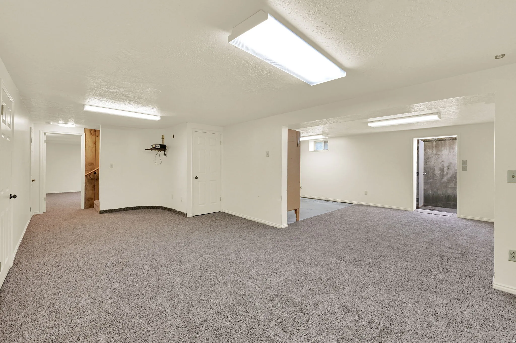 Finished below grade area featuring a textured ceiling and light colored carpet