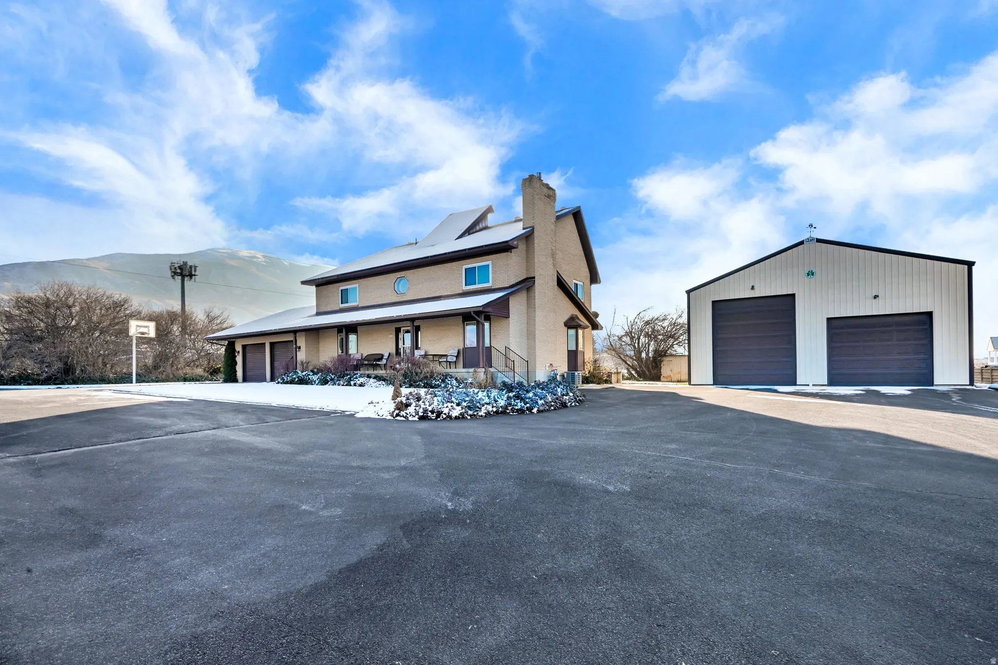 Winter View of front of home featuring an outdoor structure, a chimney, covered porch, a mountain view, and a garage
