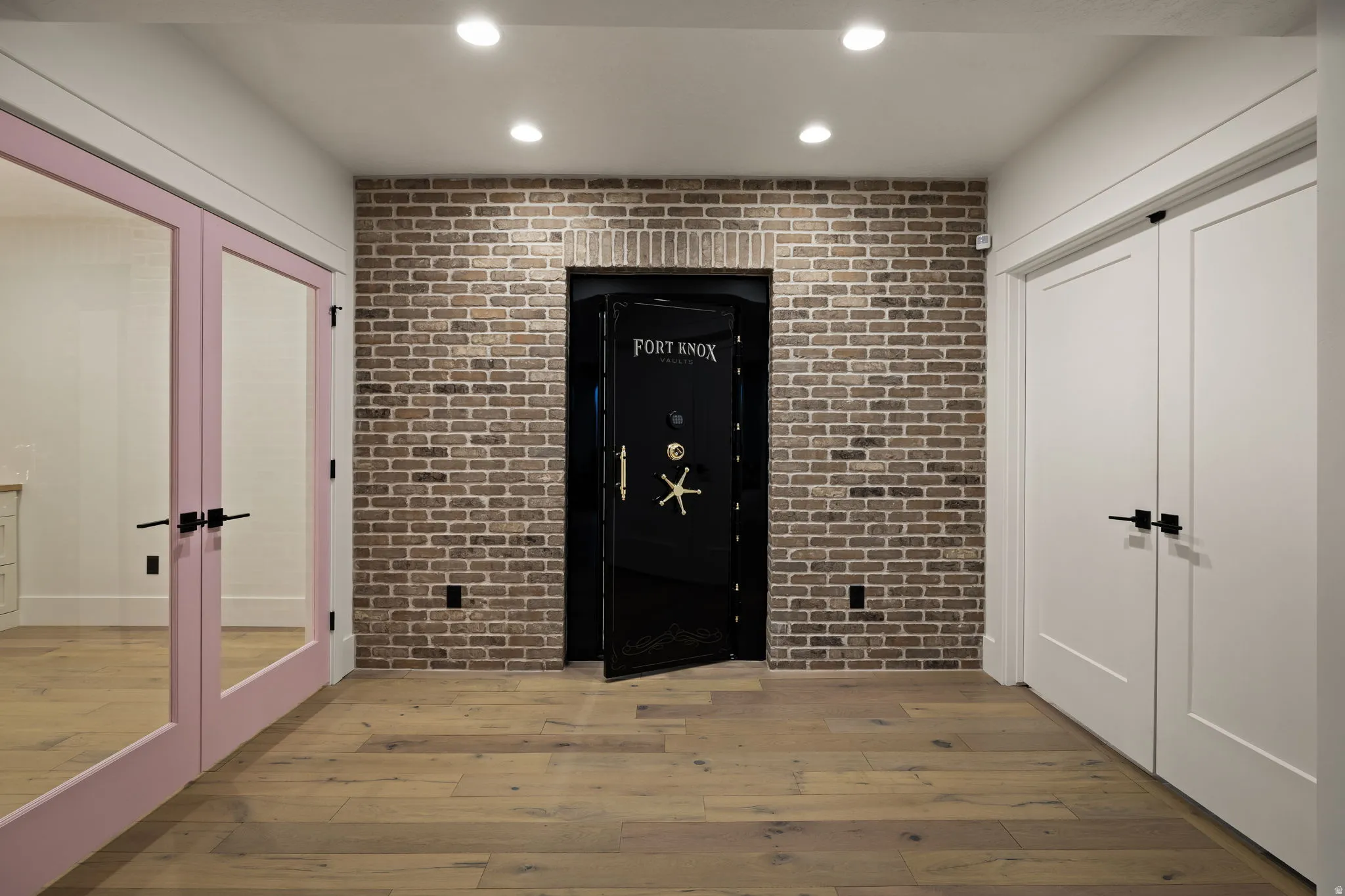 Foyer featuring brick wall, recessed lighting, light wood-type flooring, french doors, and an accent wall